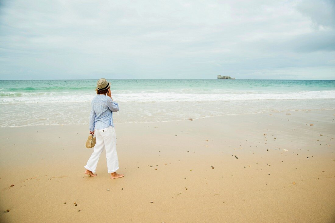 A woman on the phone walking along the beach (Camaret-sur-Mer, France)