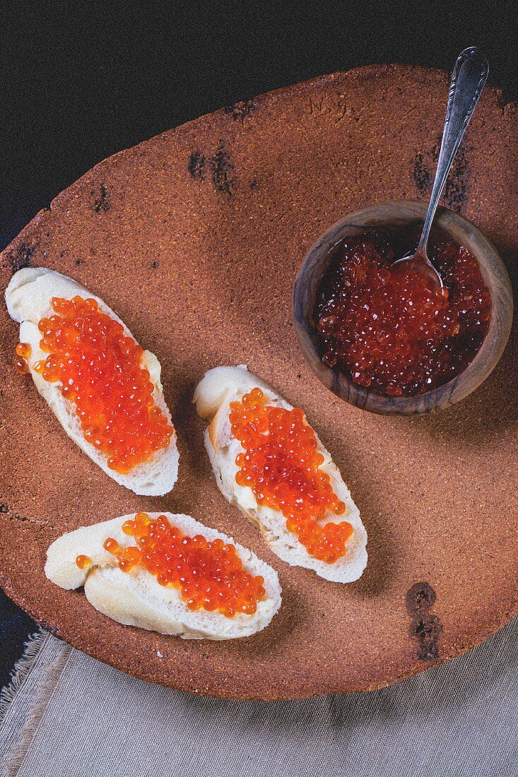 Baguettescheiben mit rotem Kaviar auf alter Tonplatte