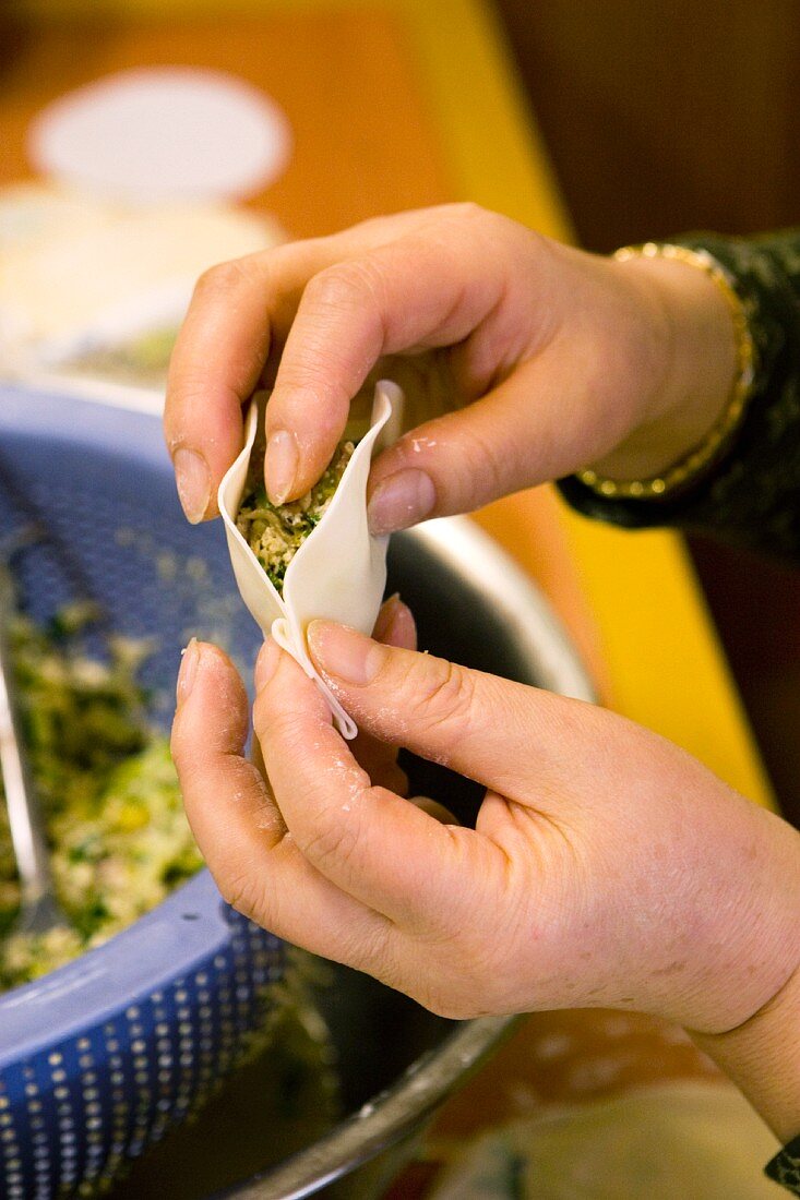 A chef filling a noodle dough parcel in an oriental restaurant