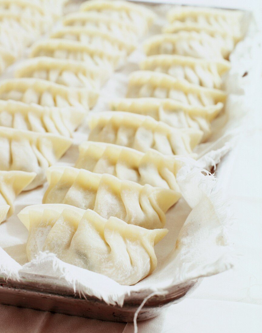Unsteamed, raw pasta parcels filled with pork on a cotton cloth
