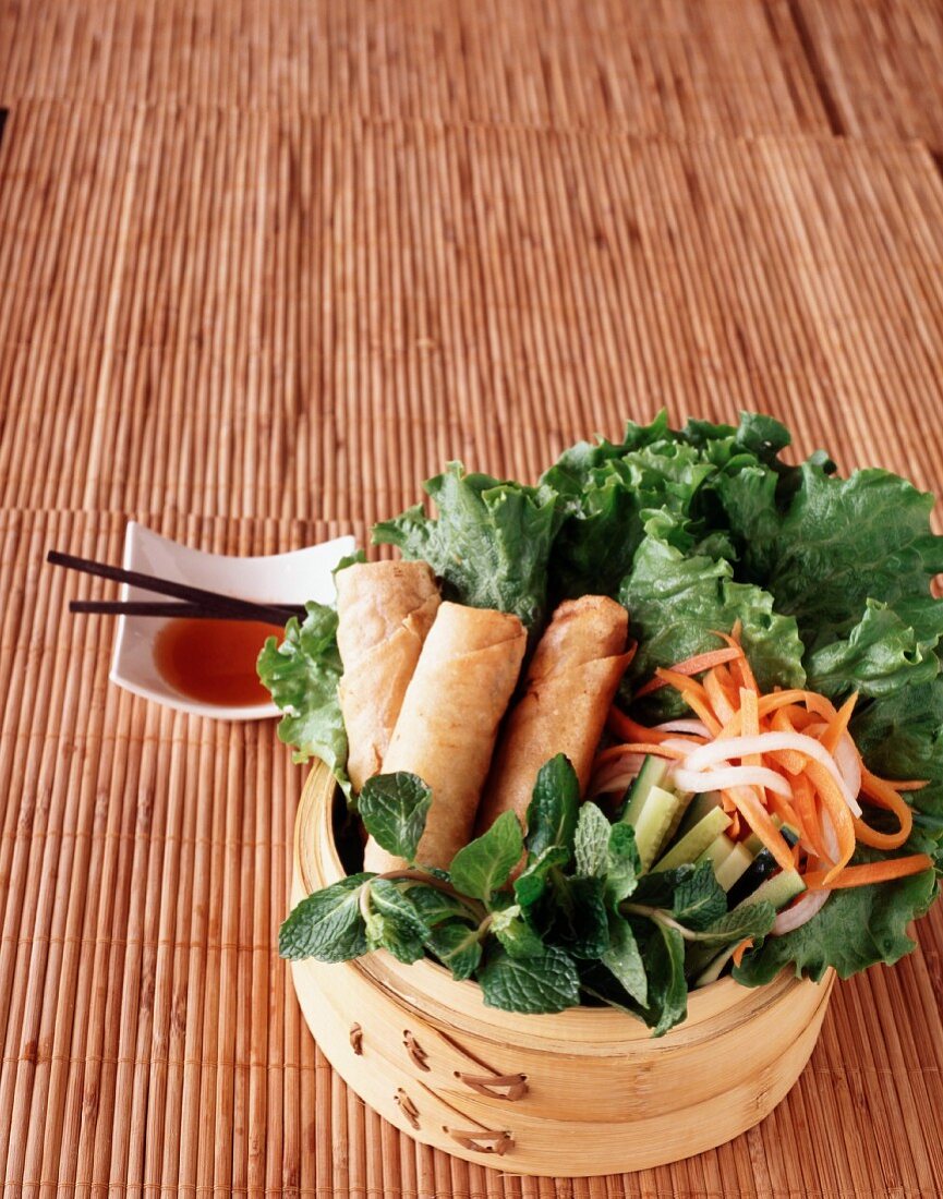 Vegetarian spring rolls on a bed of lettuce with daikon radish and carrots served with sweet chilli sauce