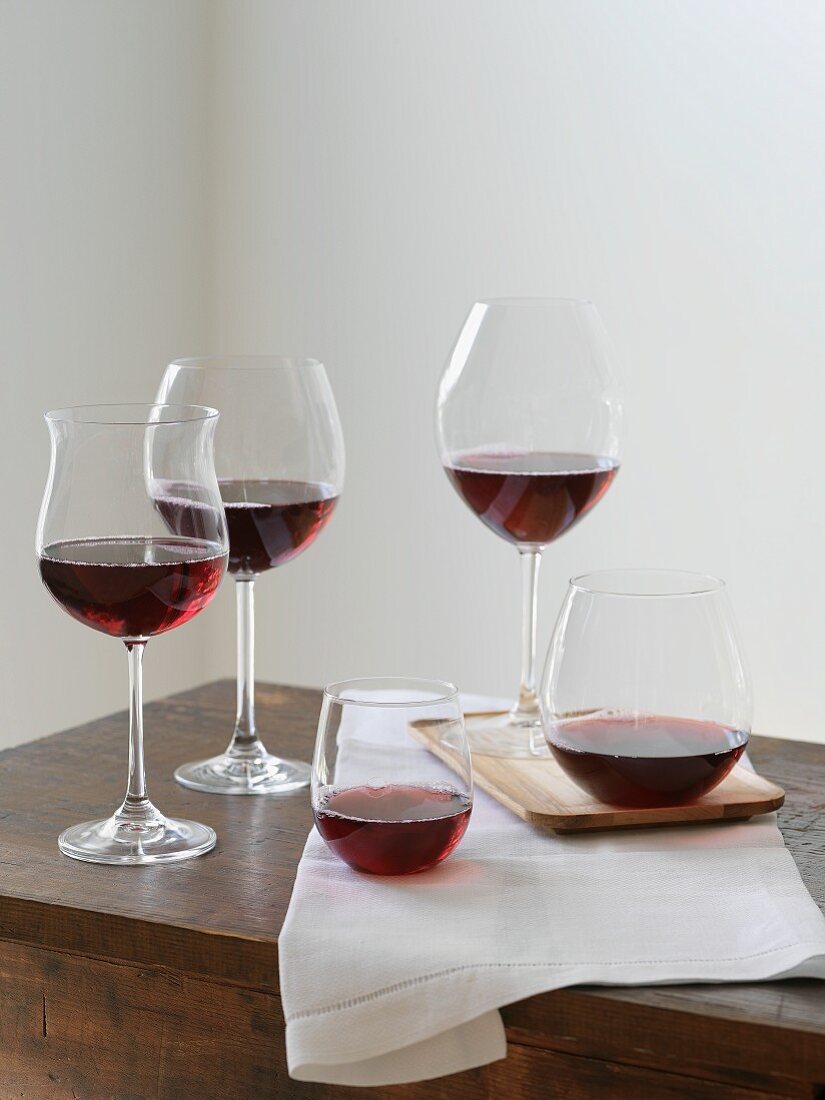 Various types of red wine glasses on a wooden table