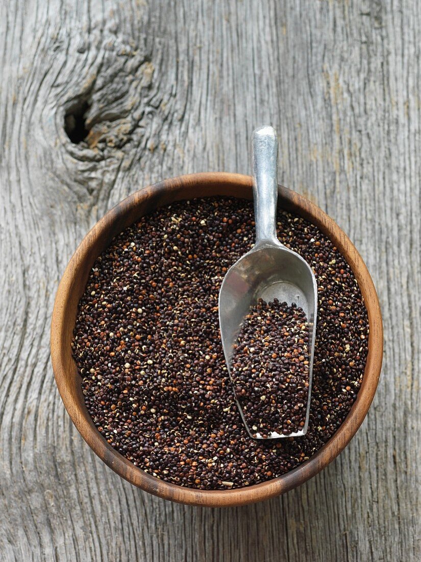 Black quinoa in a wooden bowl with a scoop