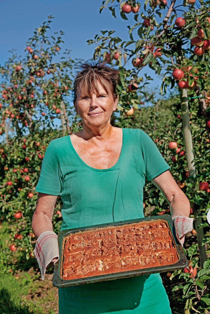 Frau hält Backblech mit Apfelkuchen