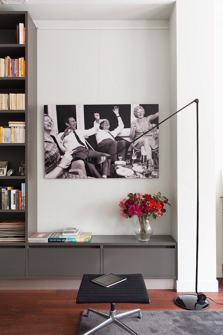 Black and white picture above sideboard, designer standard lamp and footstool in modern interior