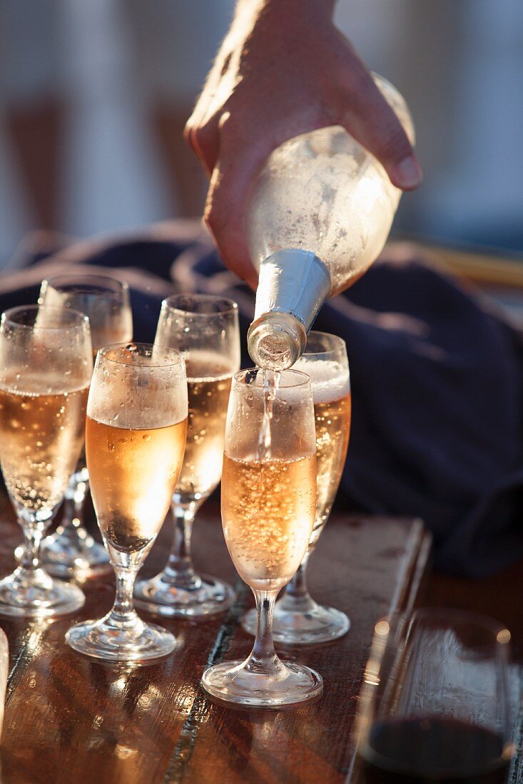 Champagner in sechs Gläser einschenken