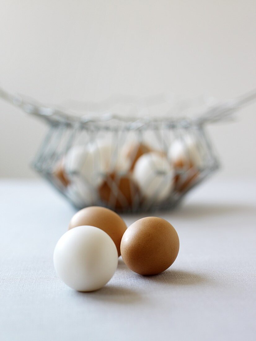 weiße und braune Eier vor Drahtkorb
