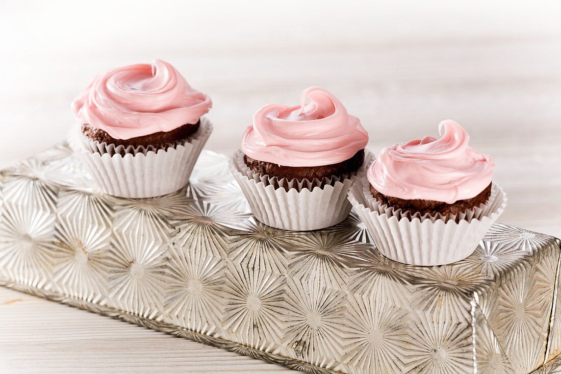 Three chocolate cupcakes with pink frosting