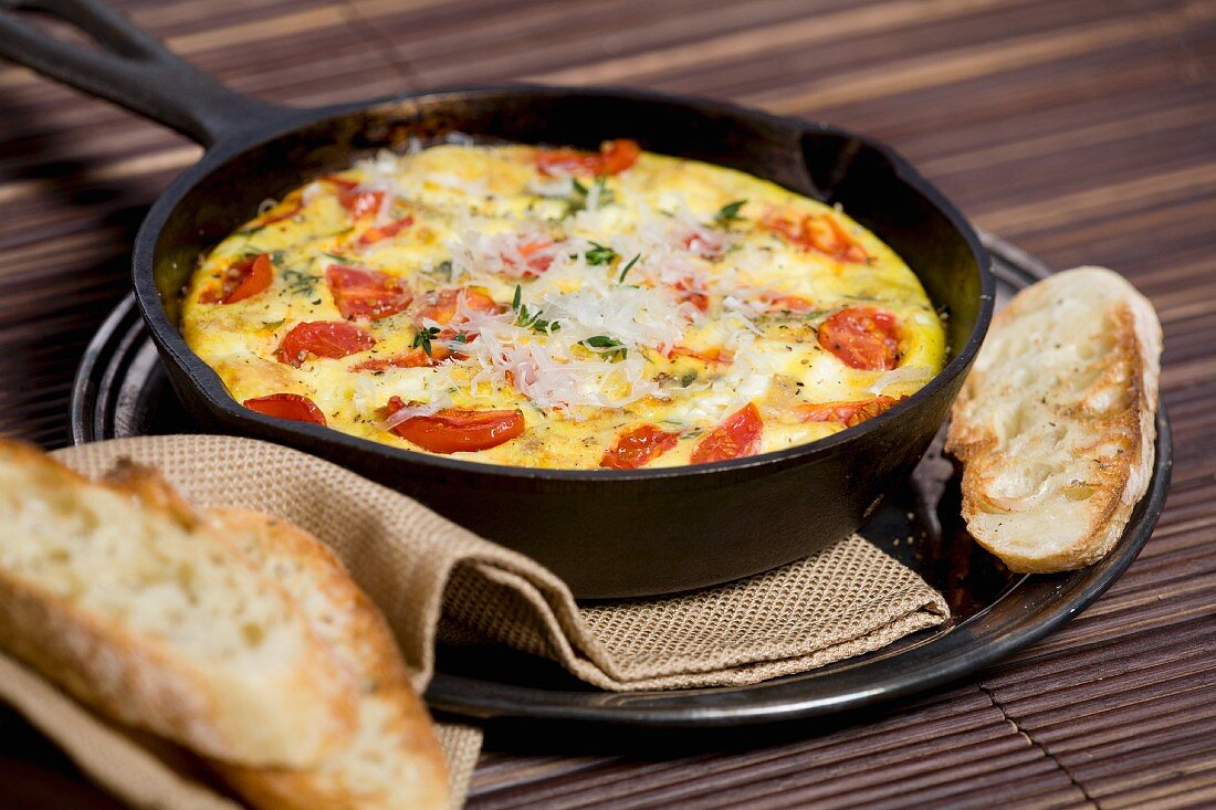 Tomato, fresh herbs and cheese frittata in a cast iron pan