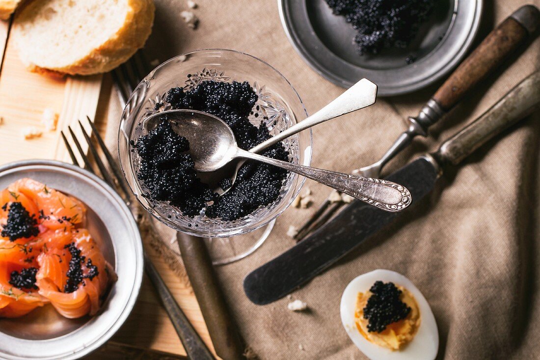 Schwarzer Kaviar in Kristallschale, auf Lachsröllchen und hartgekochtem Ei