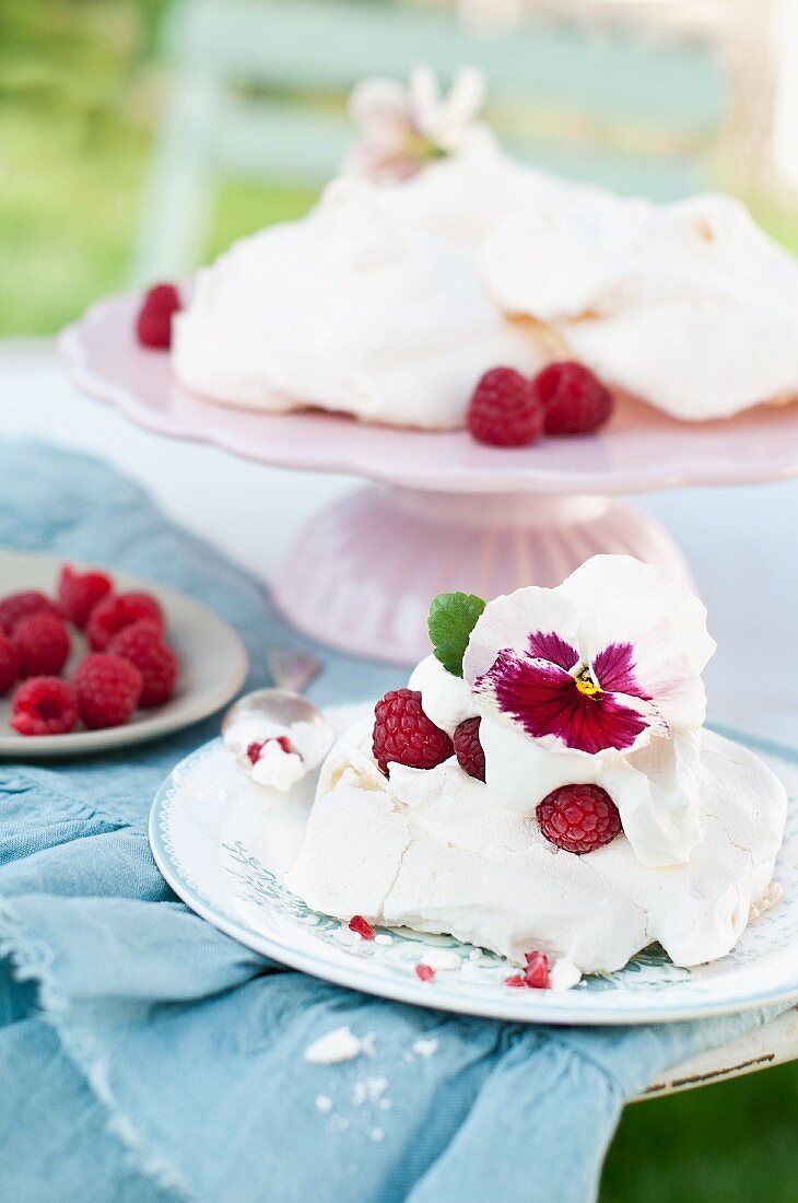 Stiefmütterchenblüte auf Himbeer-Pavlova mit Sahne