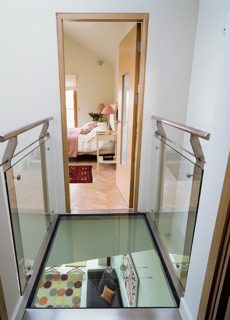 Elegant, glass bridge with views into bedroom and down into lower storey