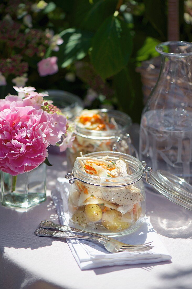 Potato salad with chicken and vegetable strips in preserving jars for picnic
