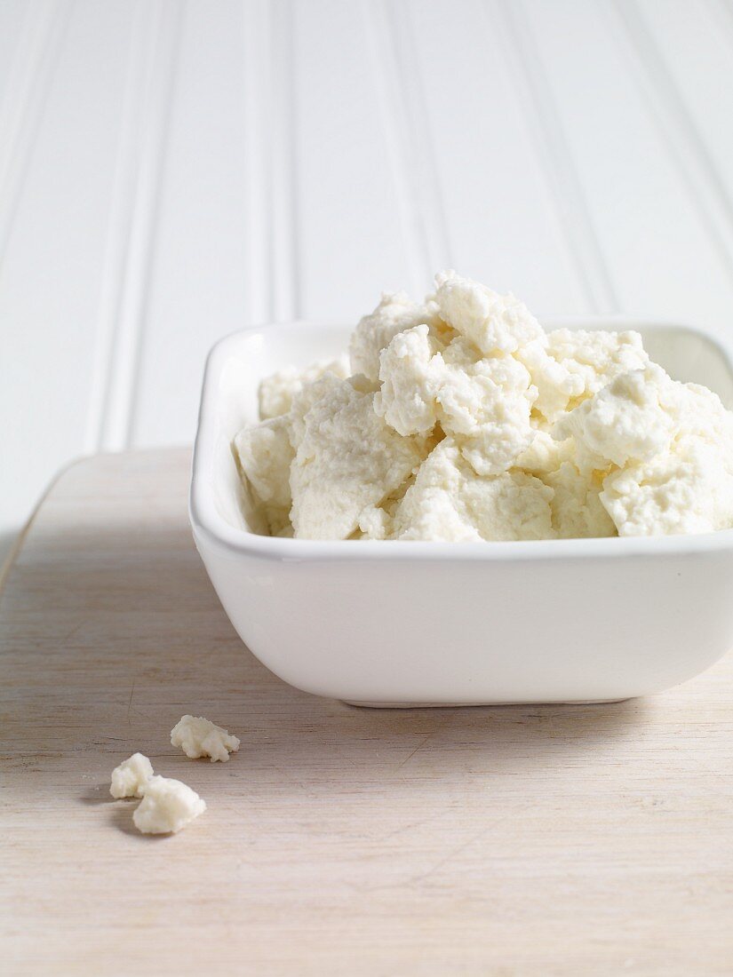 Ricotta in einem Schälchen auf Holzbrett