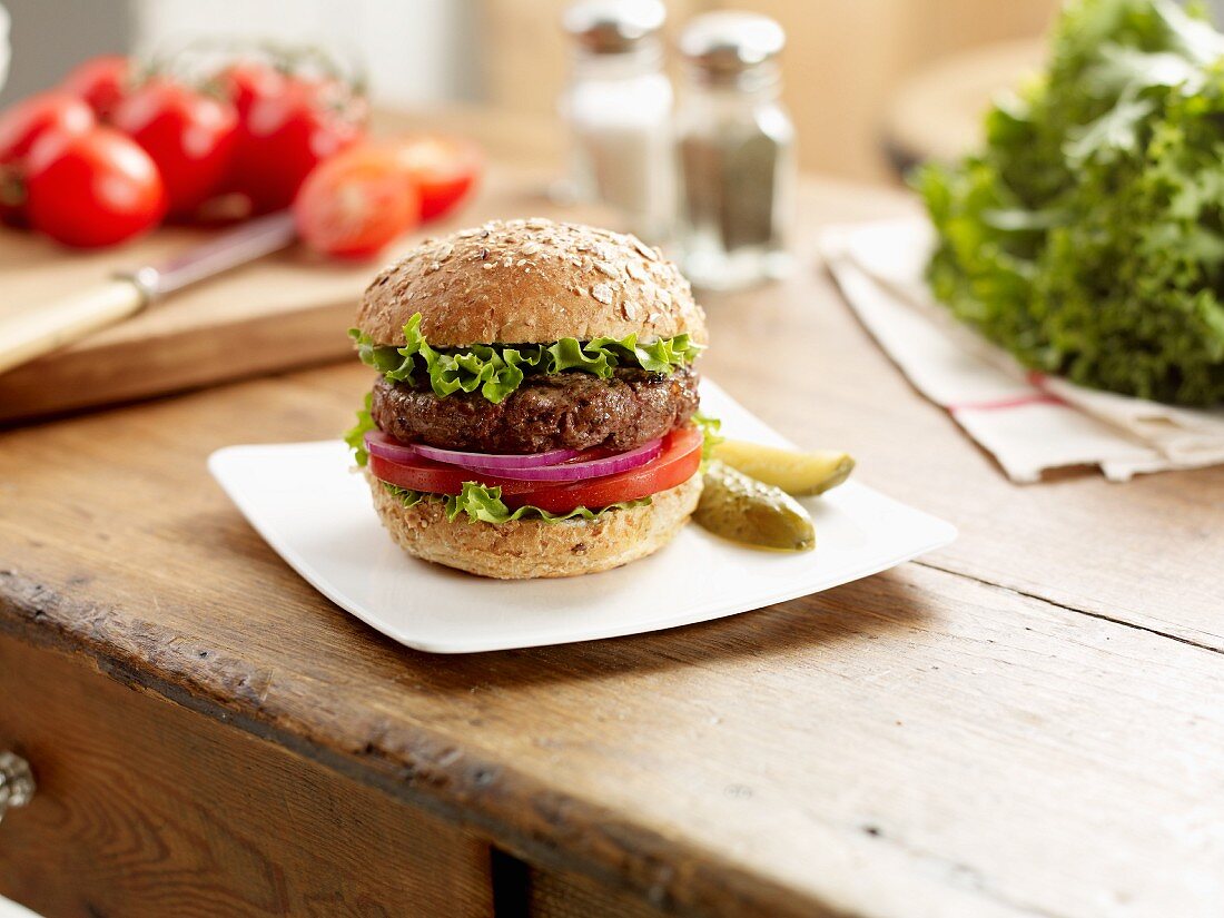 Hamburger mit Tomate, roter Zwiebel und Salat auf einem Küchentisch