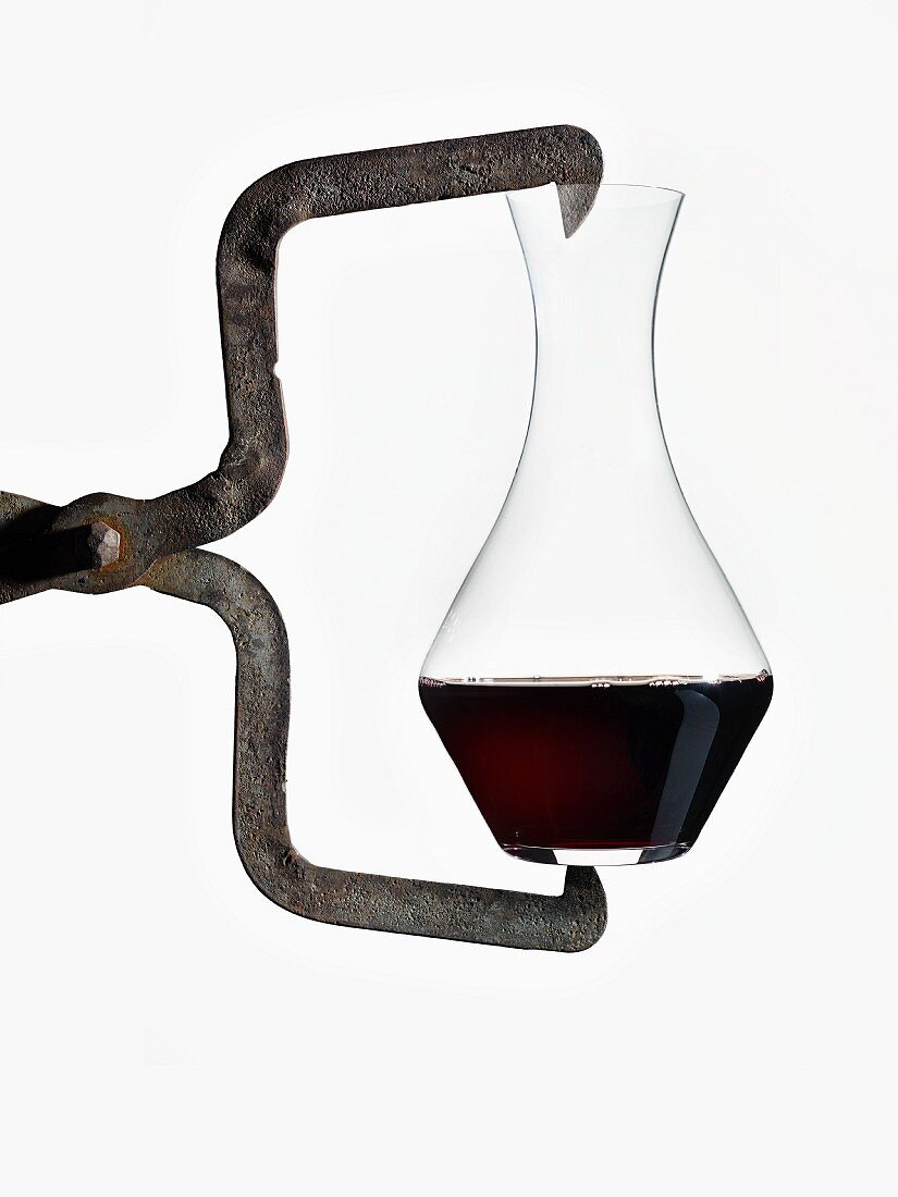 Eine Karaffe Rotwein, von Eisenwerkzeug gehalten