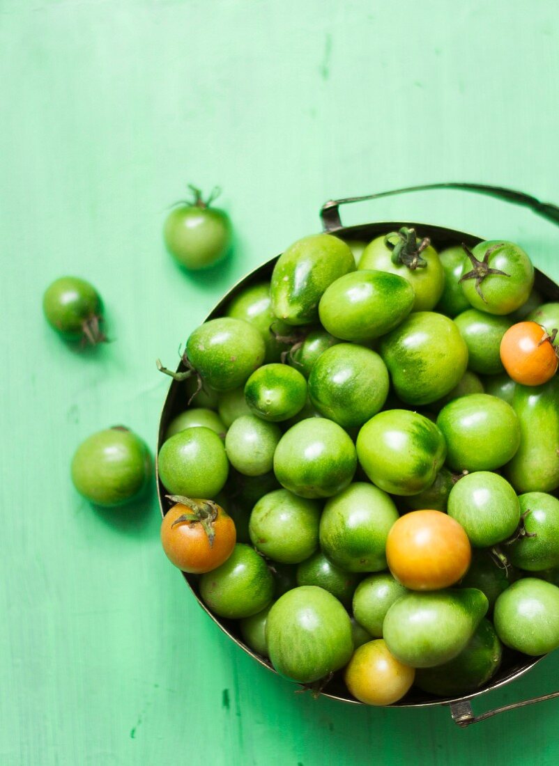 Green tomatoes in a metal bowl (seen from above)