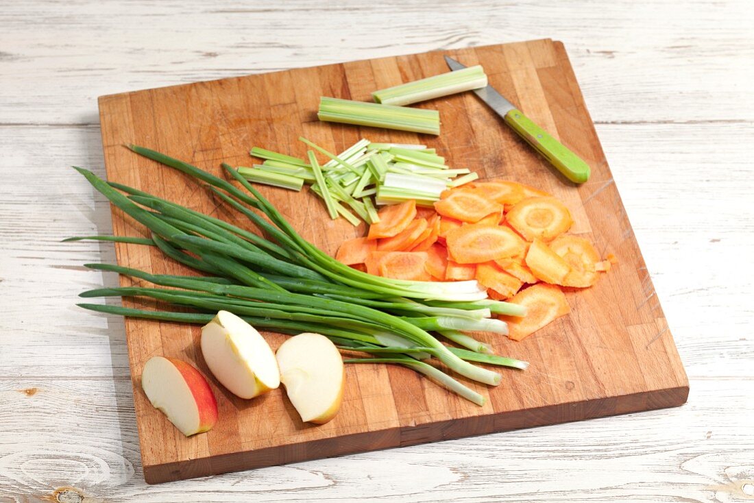 Sliced vegetables and apples on a chopping board