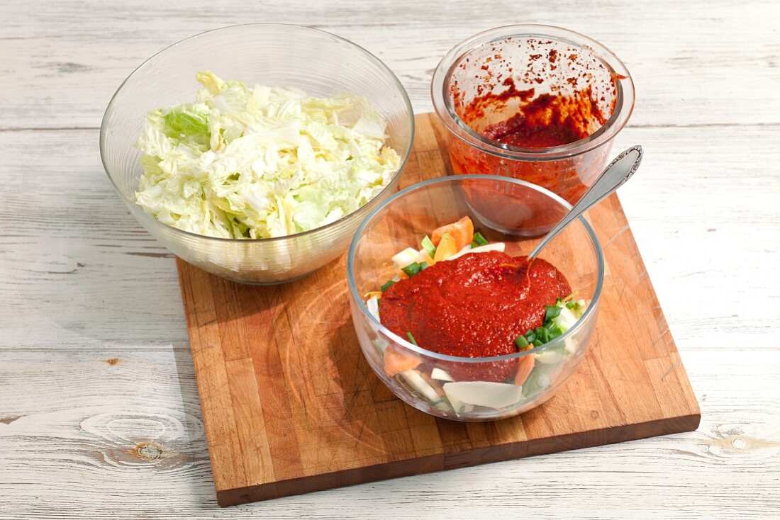 Geschnittenes Gemüse mit Chilipaste und gesalzener Chinakohl auf Schneidebrett (Zutaten für Kimchi)