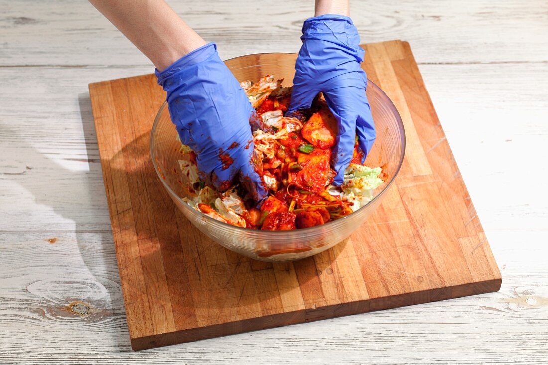 Kimchi zubereiten: gesalzenen Chinakohl mit Chilipaste vermischen