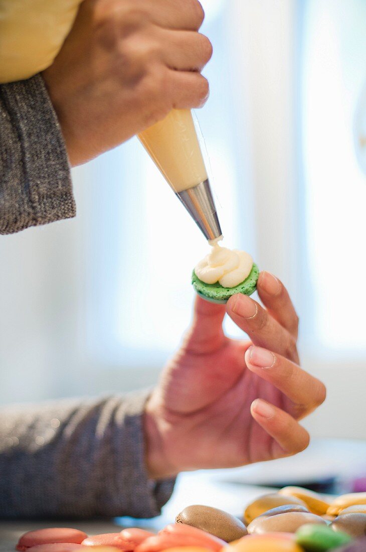 Frau verziert Macaron mit Sahnecreme