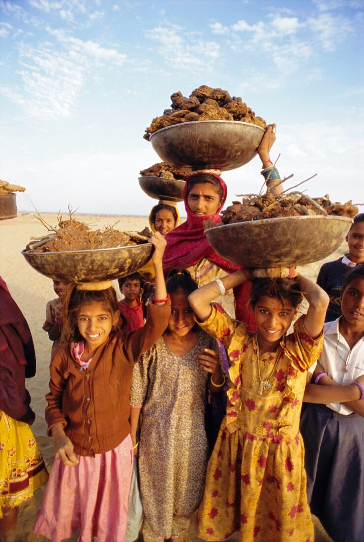 Frauen und Kinder mit gesammeltem Dung für ihr Kochfeuer; Rajasthan, Indien