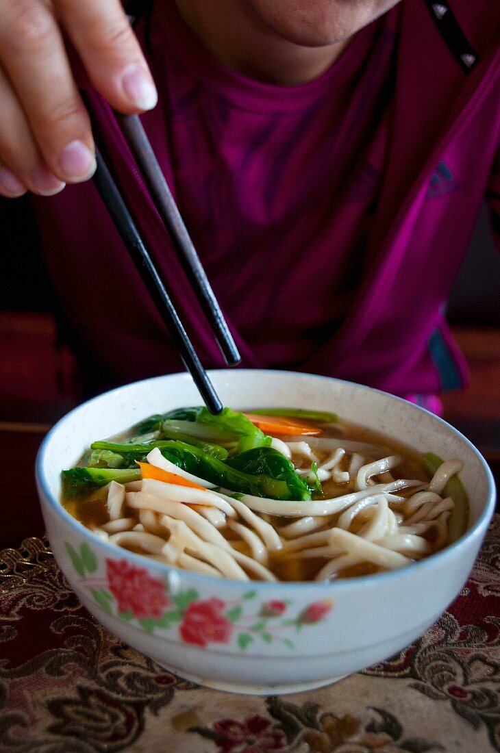 A woman eating noodle soup, Lhasa, Tibet, China, Asia