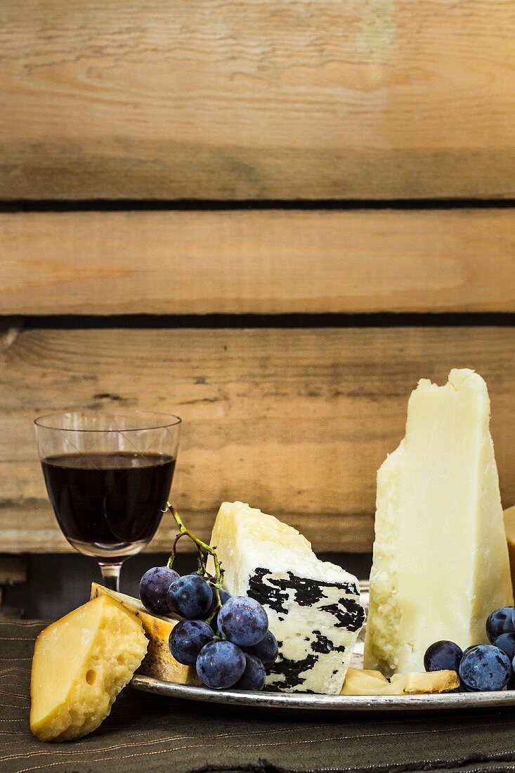 Käseteller mit Trauben vor einem Glas Rotwein