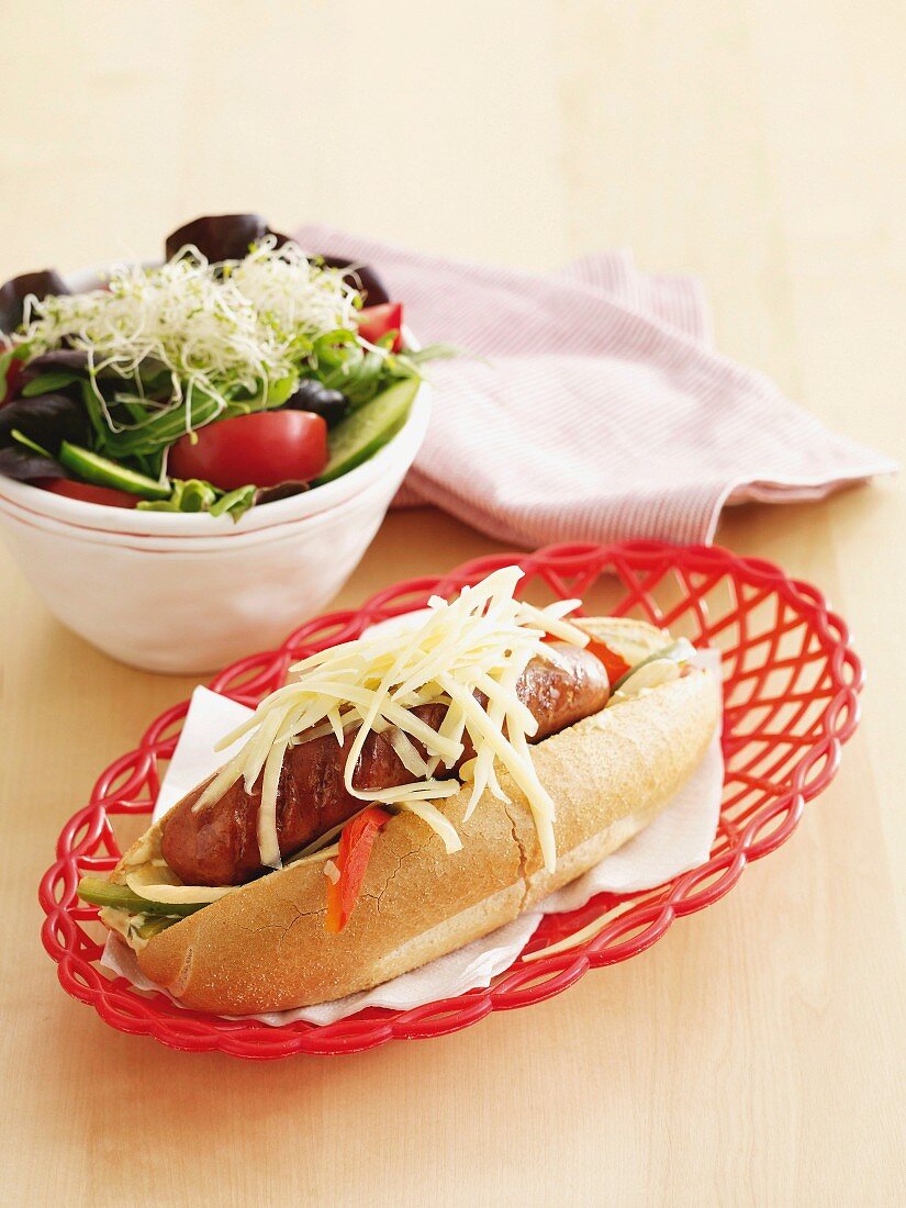 Hot dog with peppers and cheese and side salad