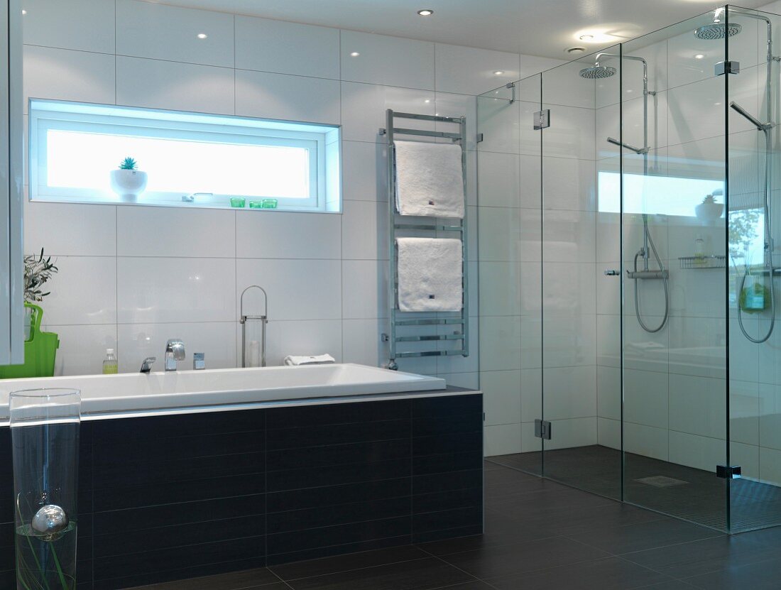 Bathroom in austere light grey, charcoal and white with floor-level twin shower behind glass screen