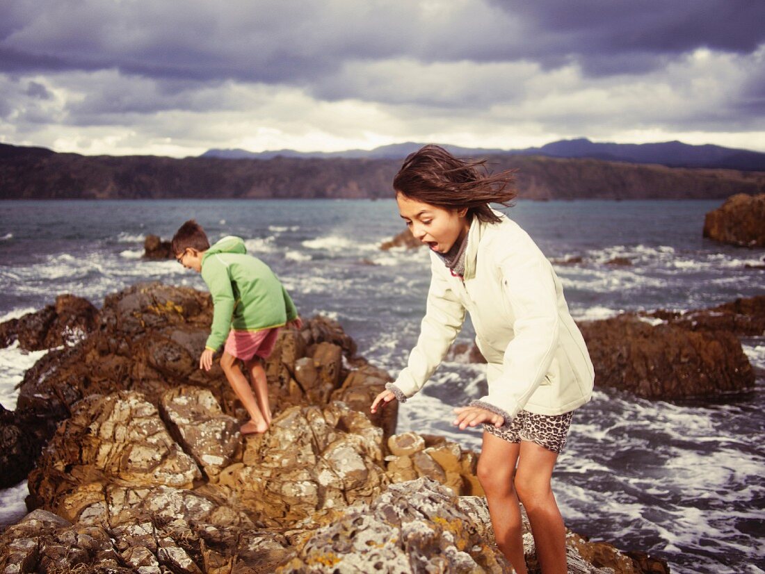 Brother and sister playing on rocky beach