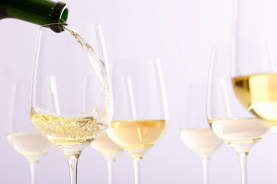 White Wine Pouring from Bottle into Glass; White Background 