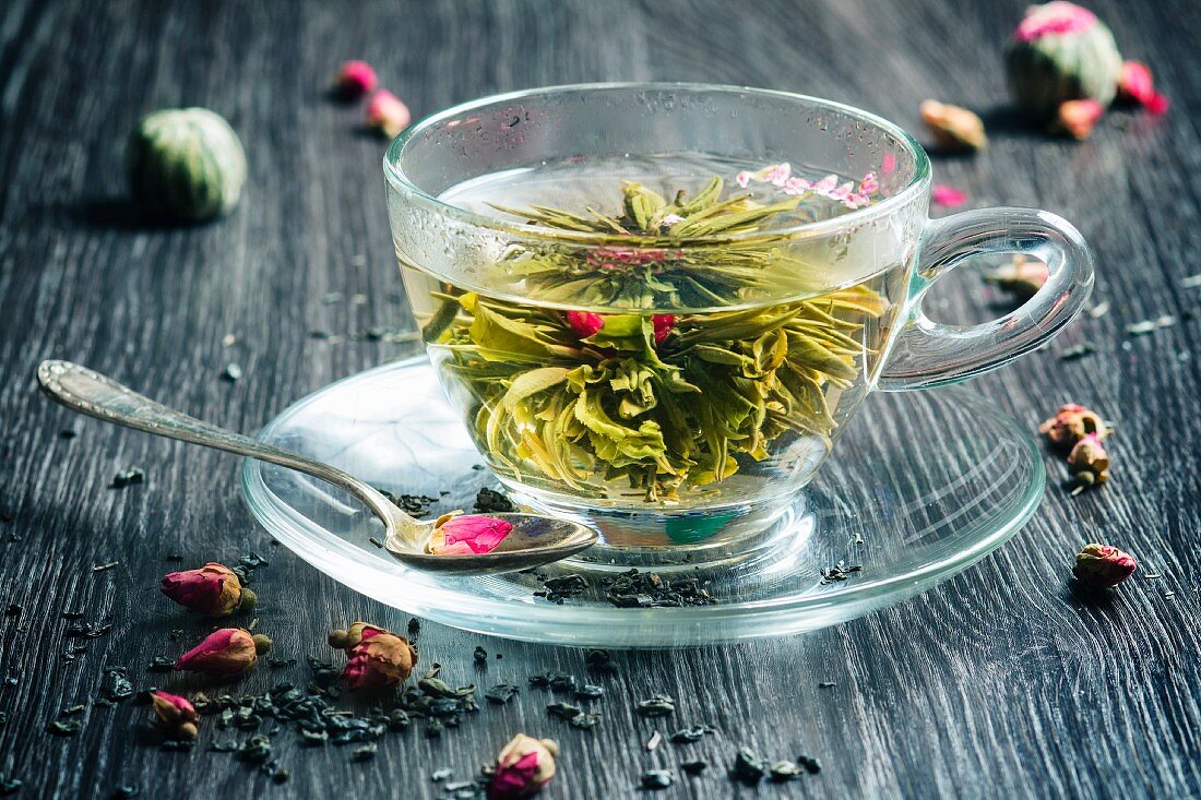 Glastasse mit grünem Tee und Teeblume