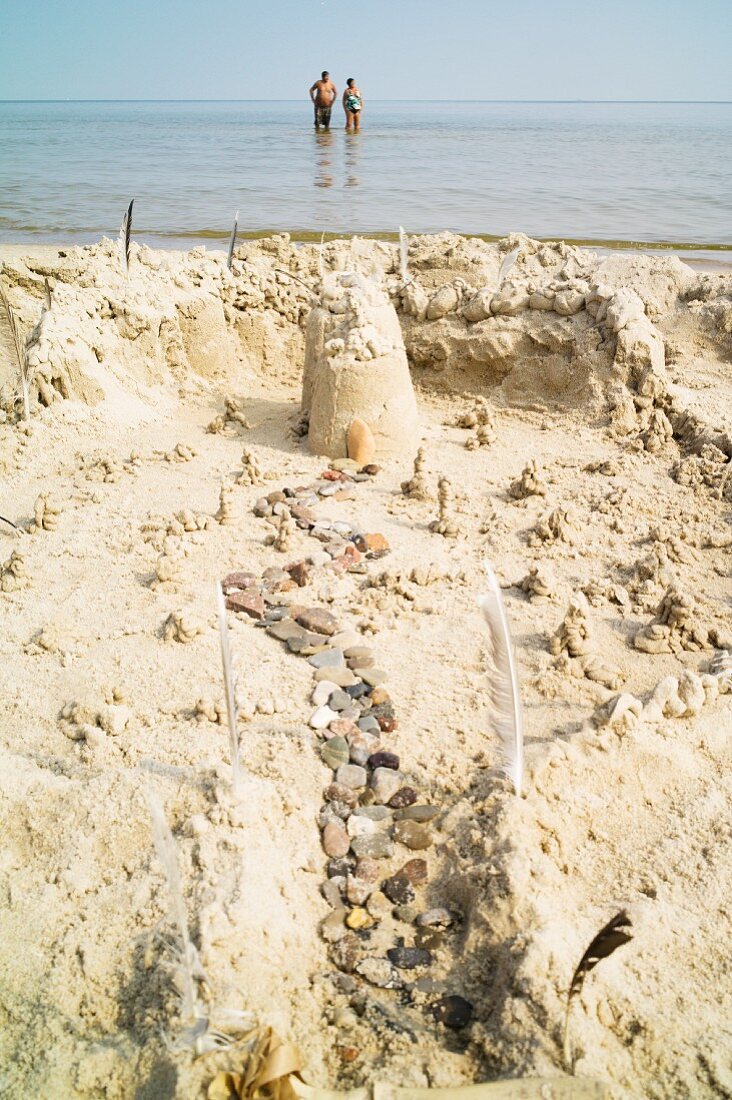 Sandburg mit Federn am Strand von Heringsdorf auf der Insel Usedom