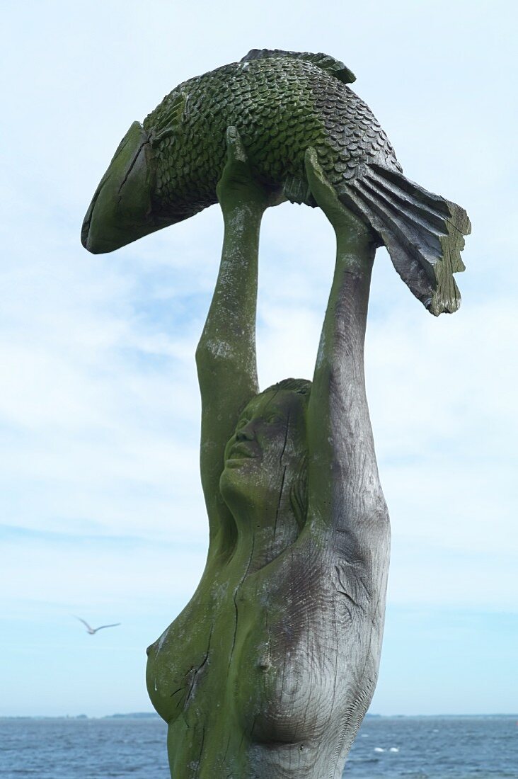 Holzstatue mit Fischr am Hafen von Neuendorf, Hiddensee