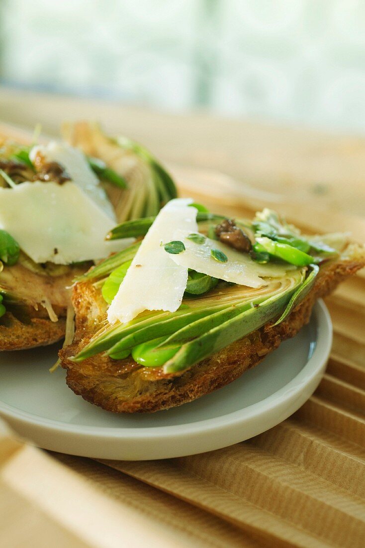 Crostini topped with artichokes, fava beans, Parmesan cheese and anchovy sauce