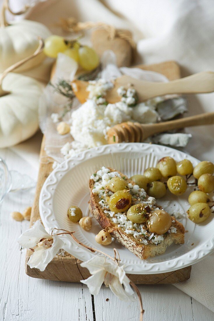 Crostino topped with goat's cheese, thyme, honey and grapes