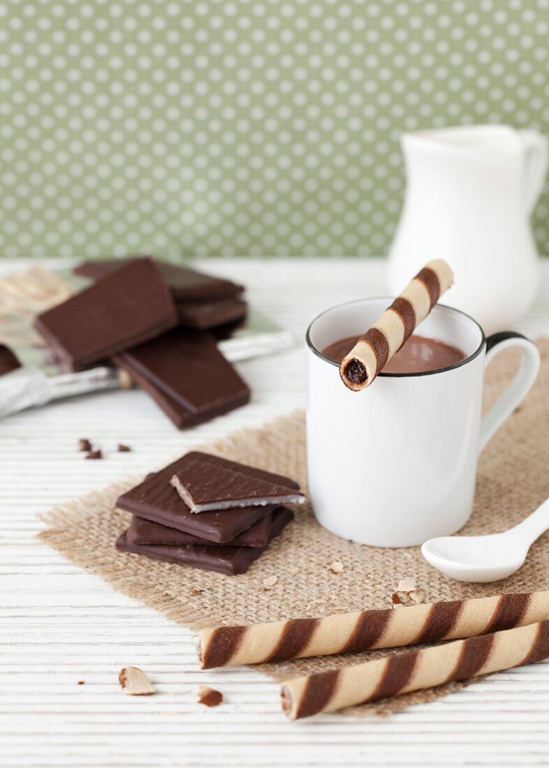 Ein Becher Heiße Schokolade mit Schoko-Minz-Blättchen und Hippenröllchen