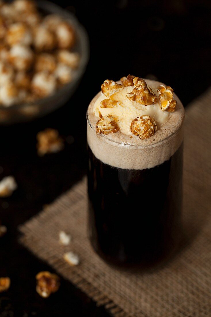 A glass of cola topped with vanilla ice cream and caramel popcorn