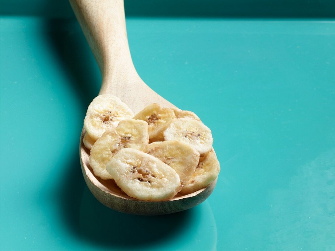 Dried banana chips on a wooden spoon