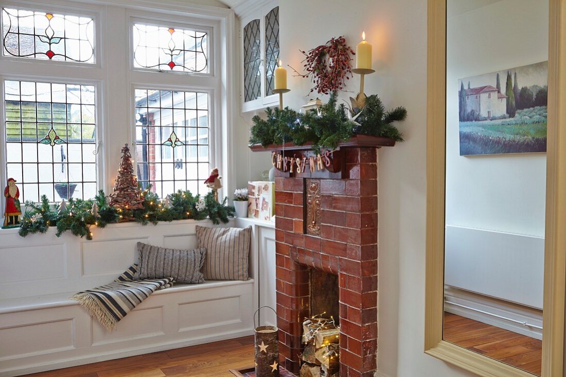 Open fireplace with brick surround and window seat with Christmas decorations on windowsill