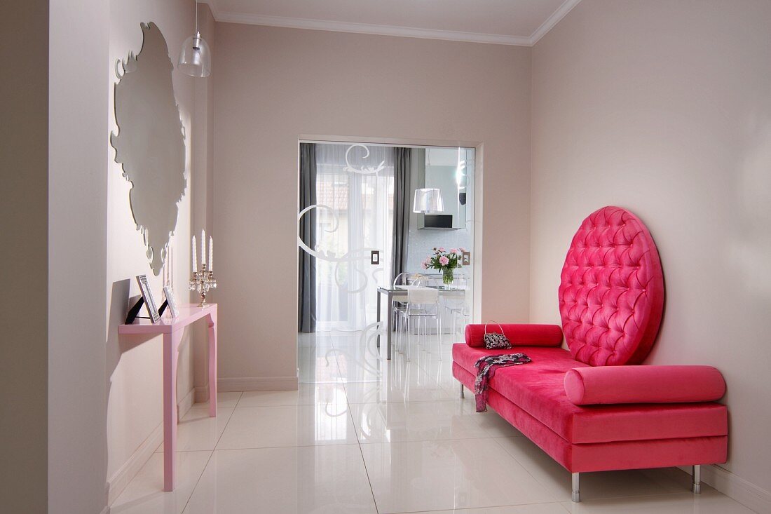 Pinkfarbene Tagesliege mit rundem Rücken-Polsterteil und rosafarbener Konsolentisch mit Wandspiegel in modernem elegantem Dielenbereich