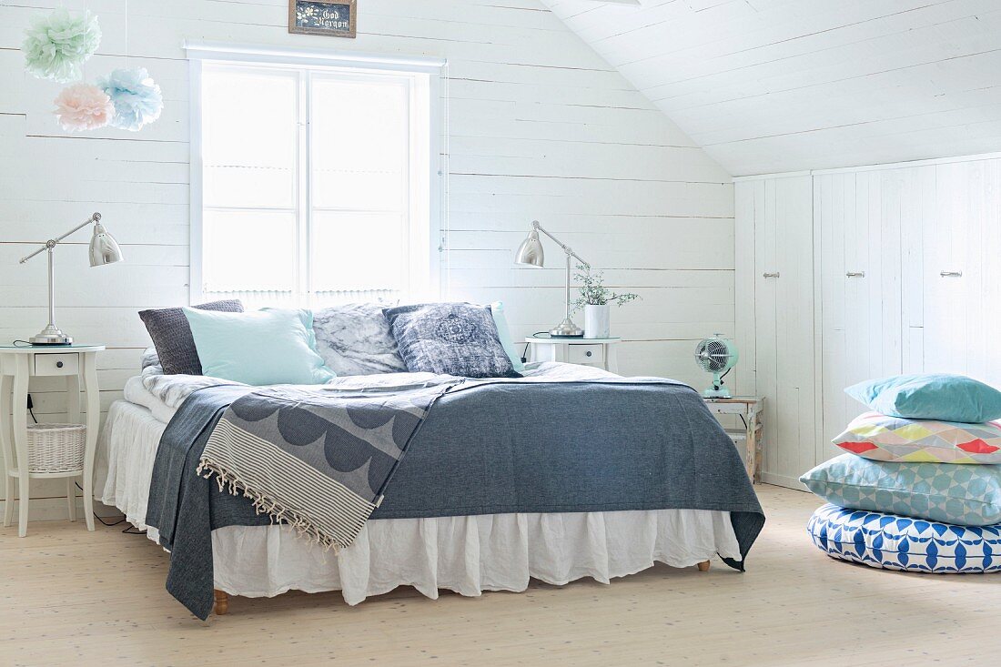 Double bed with grey patterned bedspreads in wood-clad attic room
