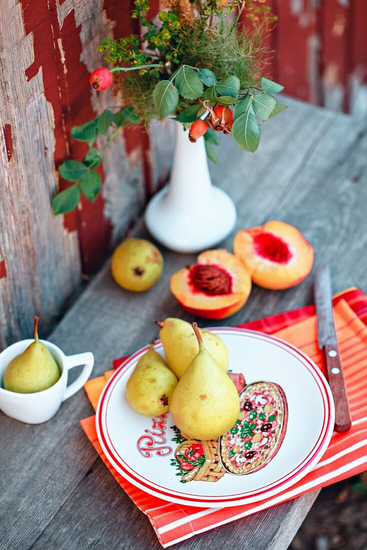 Pfirsiche und Birnen auf Holztisch im Garten