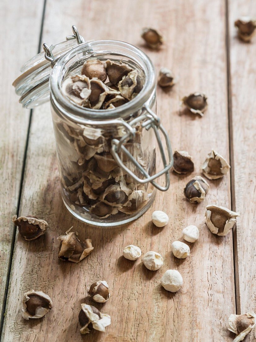 Moringa seeds in a jar on a wooden surface
