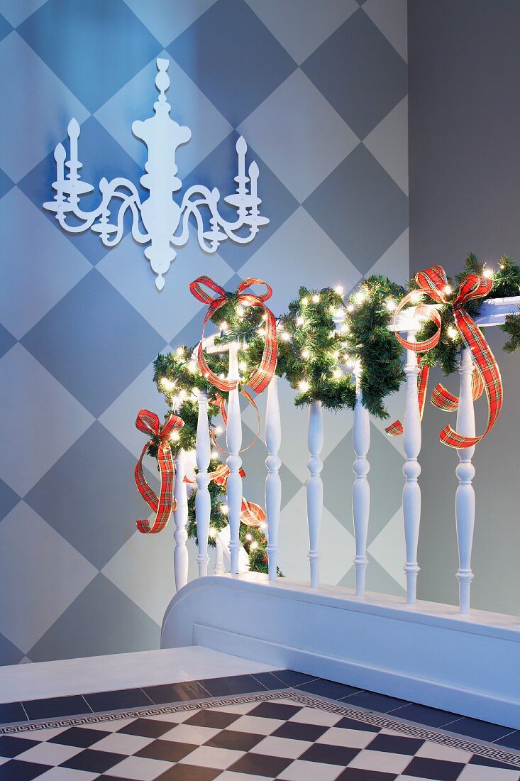 Weihnachtlich dekoriertes Treppengeländer, Wand im Schachbrettmuster mit Kerzenleuchter-Silhoutte
