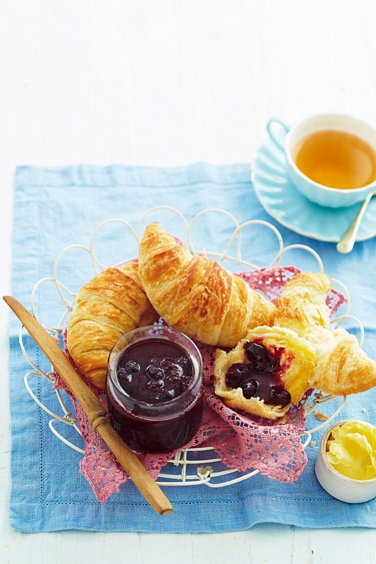 Red grape jam with fresh croissants, butter and cup of tea