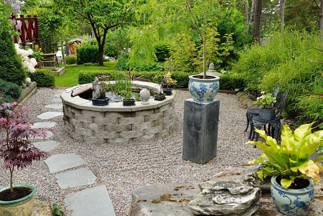 Oriental-style elements on gravel terrace; stone-edged pond and planter with blue and white Chinese pattern on plinth