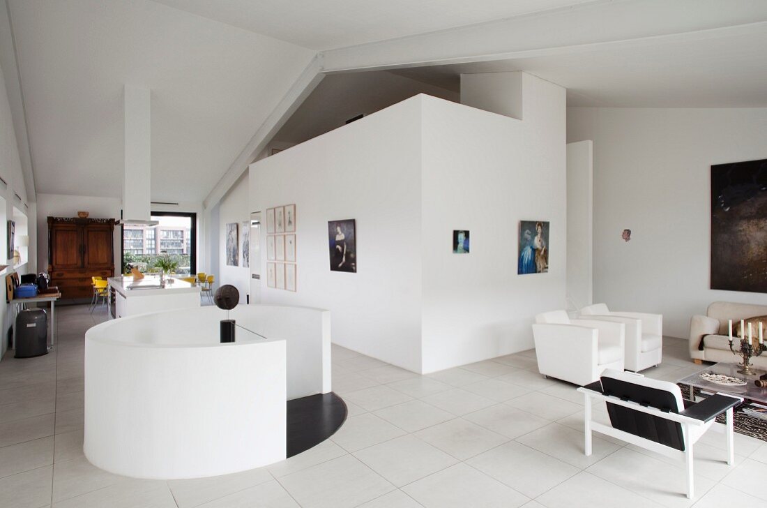 Modern loft apartment with round white balustrade around stairwell and minimalist lounge area