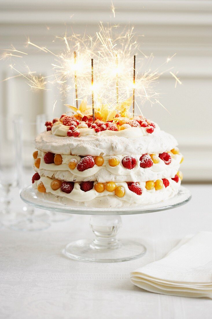 A festive pavlova with cream, berries and burning sparklers